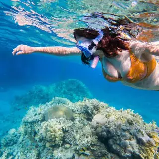 Buceadora con máscara y snorkel sobre los corales